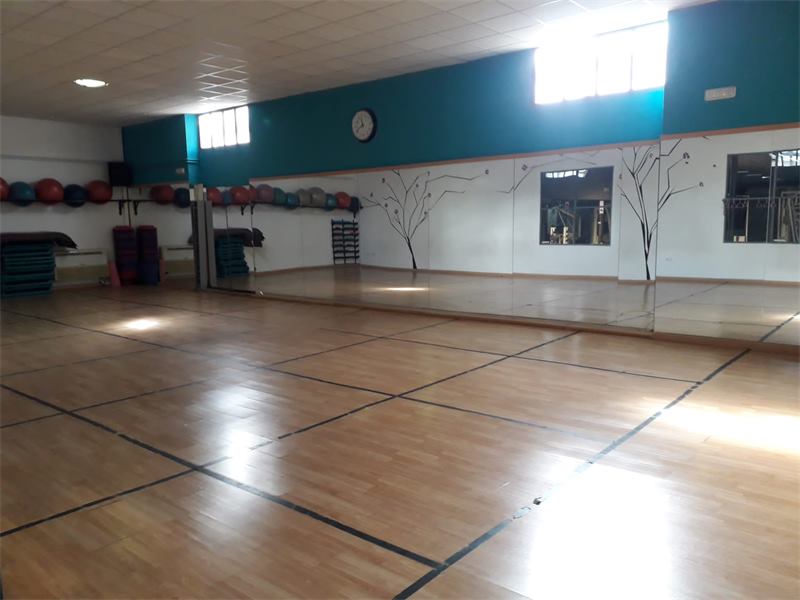 Sala de clases colectivas del Gimnasio Body Builder con suelo de parquet y espejos